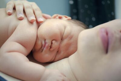 Neugeborenes Baby schläft auf der Brust seiner Mutter.